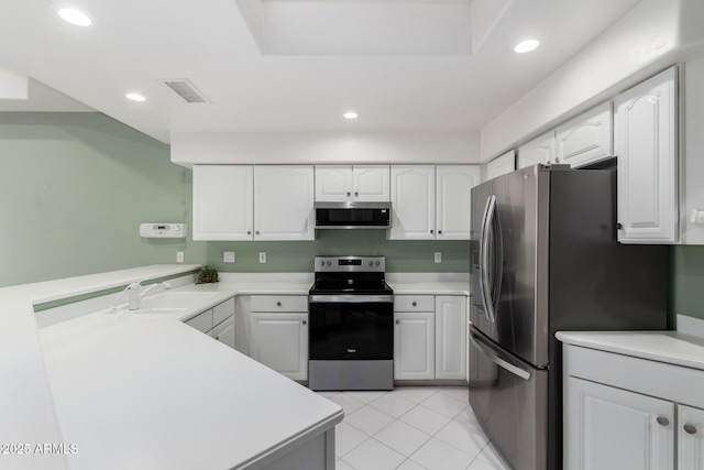 kitchen with a sink, recessed lighting, appliances with stainless steel finishes, a peninsula, and white cabinets