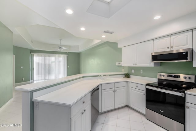 kitchen with visible vents, a peninsula, a sink, stainless steel appliances, and light countertops