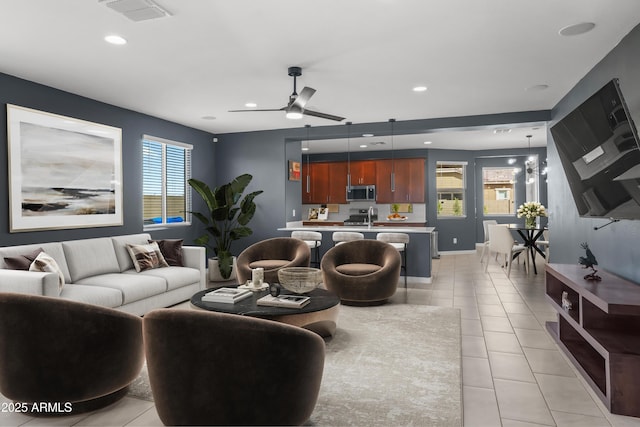 living area with visible vents, baseboards, ceiling fan with notable chandelier, light tile patterned flooring, and recessed lighting