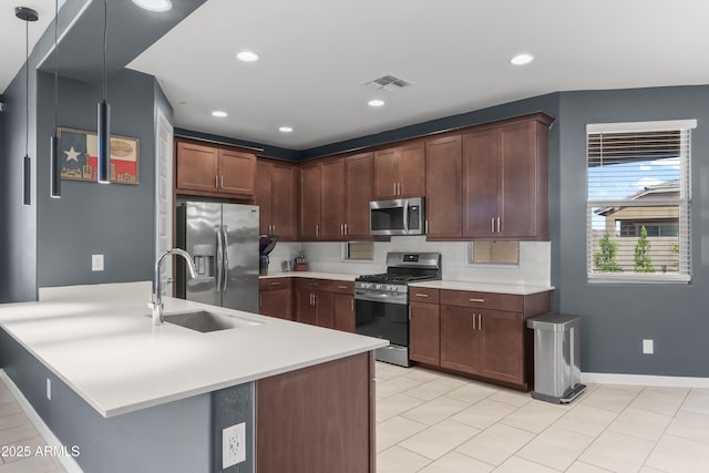 kitchen with light countertops, visible vents, backsplash, appliances with stainless steel finishes, and a sink