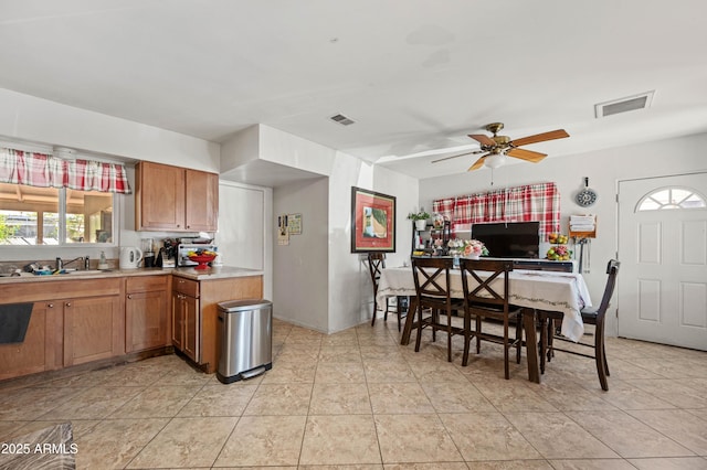 kitchen featuring brown cabinetry, visible vents, light countertops, and a sink