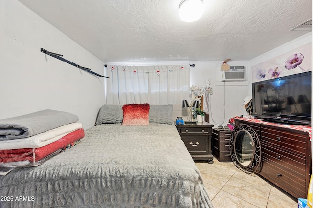 bedroom with a wall mounted air conditioner, light tile patterned floors, visible vents, and a textured ceiling
