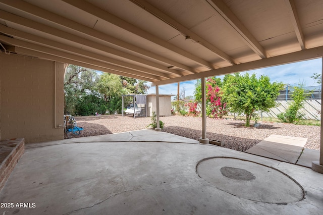 view of patio with fence, an outbuilding, and a storage unit