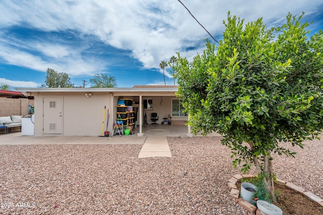 rear view of house with a patio, concrete block siding, and fence