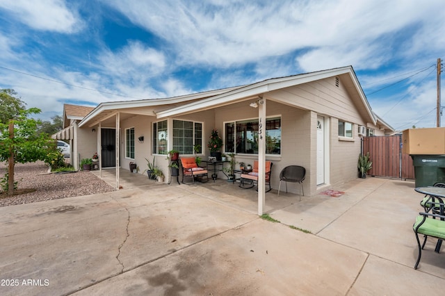 back of house with a patio area, brick siding, and a gate