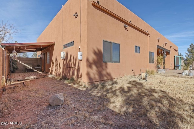 view of side of home featuring fence and stucco siding