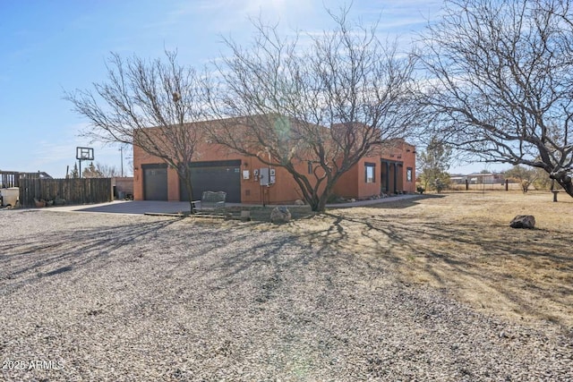 view of front facade with a garage, driveway, and fence