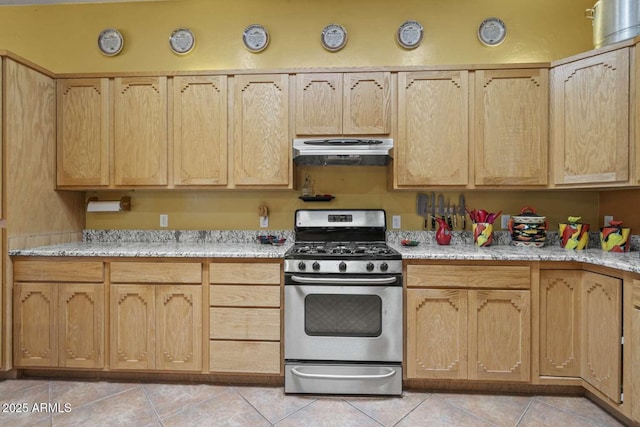 kitchen with exhaust hood, gas range, light stone counters, light brown cabinets, and light tile patterned flooring