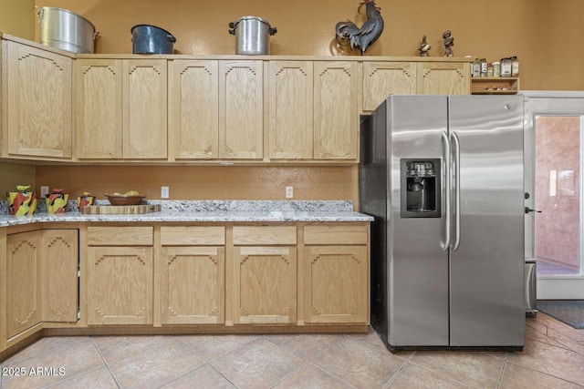 kitchen with light tile patterned floors, light brown cabinets, light stone counters, and stainless steel fridge with ice dispenser