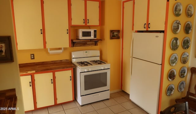 kitchen featuring white cabinets, white appliances, and light tile patterned floors