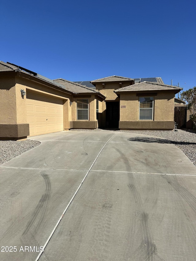 view of front of property with solar panels, an attached garage, concrete driveway, and stucco siding