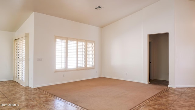 spare room with light carpet, baseboards, visible vents, and vaulted ceiling