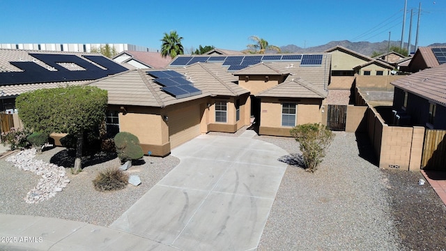 view of front of property with a tile roof, a residential view, fence, roof mounted solar panels, and stucco siding