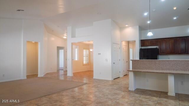 kitchen with high vaulted ceiling, freestanding refrigerator, light countertops, and decorative light fixtures