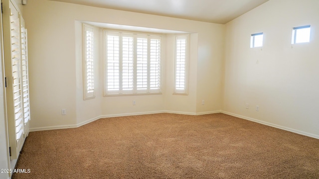 spare room with carpet, plenty of natural light, lofted ceiling, and baseboards