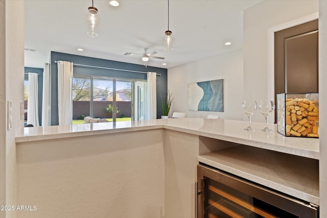 kitchen featuring pendant lighting, ceiling fan, light stone countertops, and beverage cooler