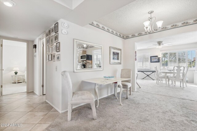 tiled dining area featuring a textured ceiling and ceiling fan with notable chandelier