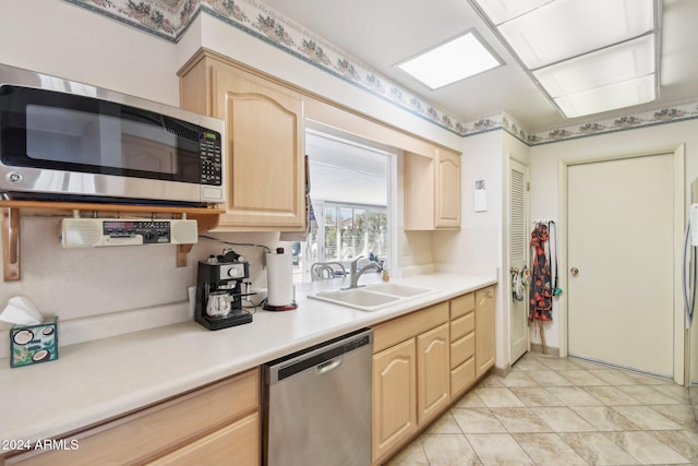 kitchen with light tile patterned floors, light brown cabinetry, sink, and appliances with stainless steel finishes