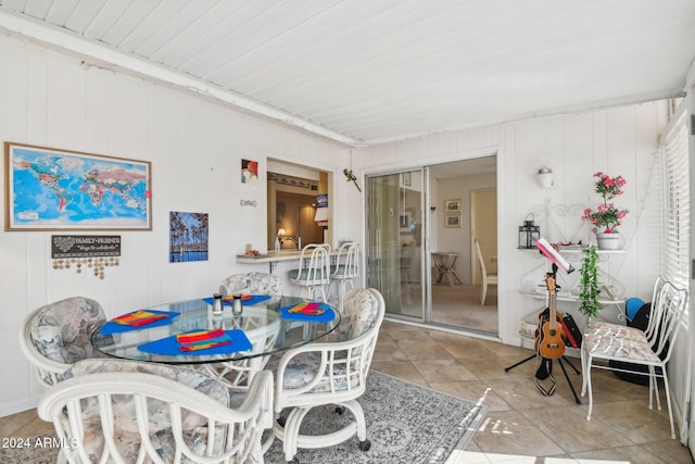 tiled dining area featuring wood walls