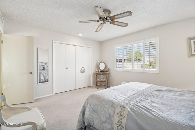 carpeted bedroom with ceiling fan, a closet, and a textured ceiling