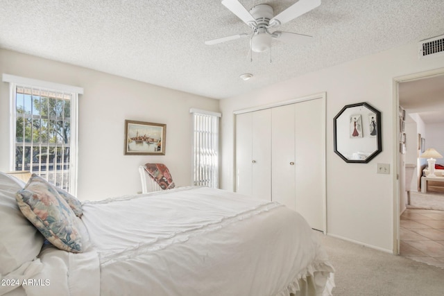 carpeted bedroom featuring ceiling fan, a closet, and a textured ceiling