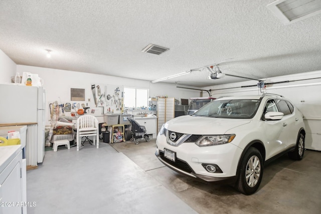 garage with a workshop area, white fridge, and a garage door opener