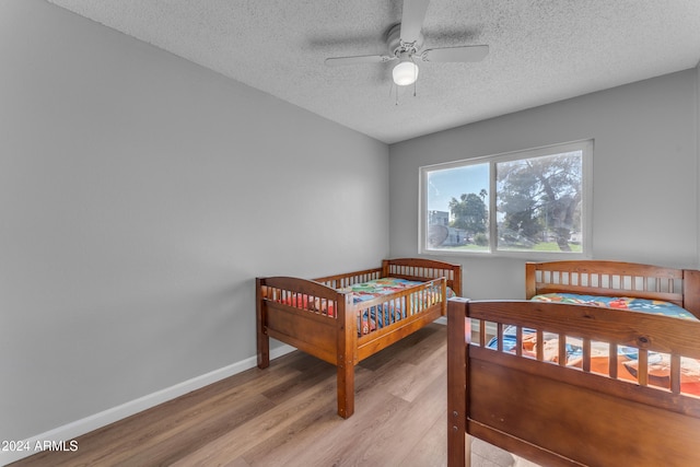 bedroom featuring ceiling fan, a textured ceiling, and light hardwood / wood-style flooring