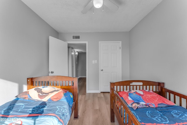 bedroom with a textured ceiling, light hardwood / wood-style floors, and ceiling fan