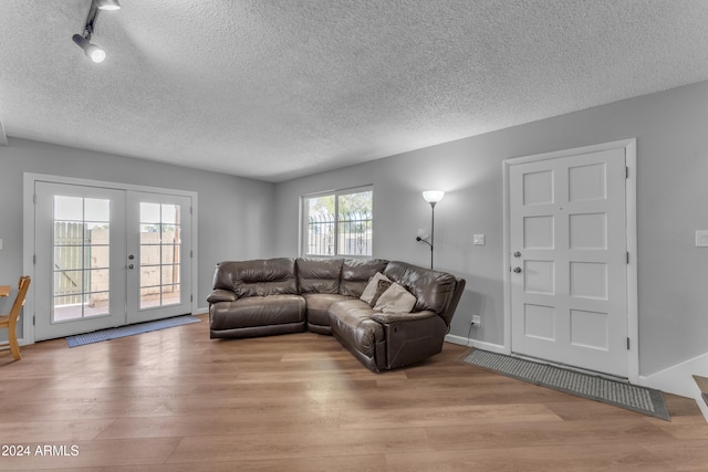 living room with a healthy amount of sunlight, a textured ceiling, and light hardwood / wood-style floors