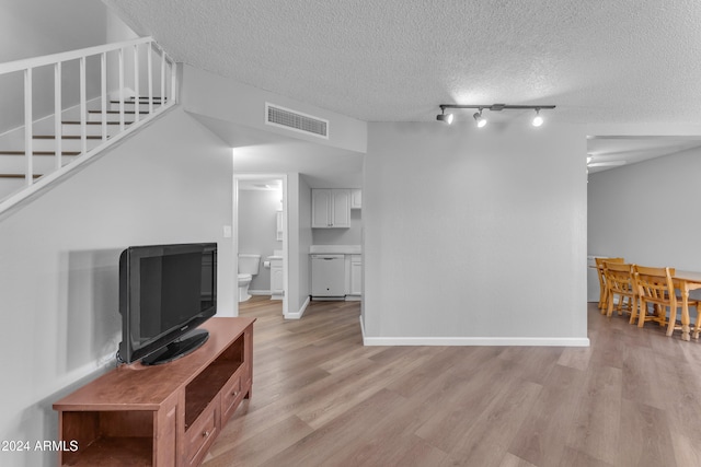 unfurnished living room featuring light wood-type flooring and a textured ceiling