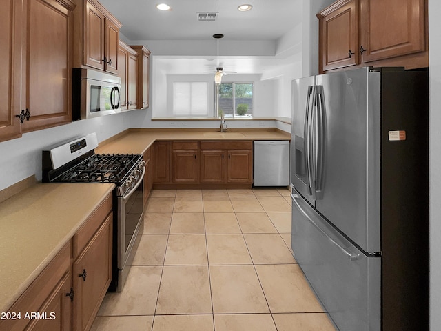 kitchen with ceiling fan, sink, light tile patterned flooring, and stainless steel appliances