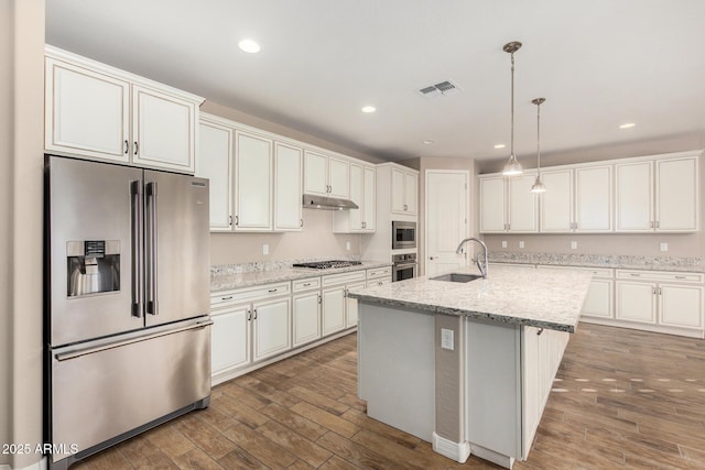 18108 W Cassia Way, Goodyear, AZ 85338 - kitchen with stainless steel appliances, wood finished floors, under cabinet range hood, decorative light fixtures, and recessed lighting