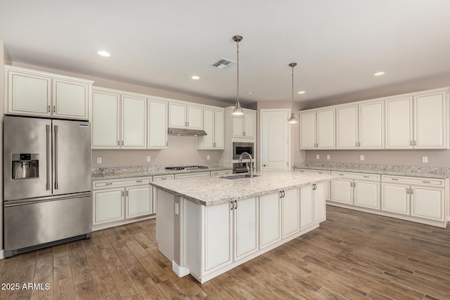 18108 W Cassia Way, Goodyear, AZ 85338 - kitchen featuring appliances with stainless steel finishes, wood finished floors, under cabinet range hood, an island with sink, and pendant lighting