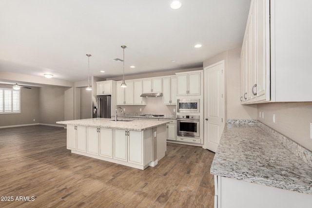 18108 W Cassia Way, Goodyear, AZ 85338 - kitchen featuring appliances with stainless steel finishes, under cabinet range hood, white cabinetry, dark wood-type flooring, and a kitchen island with sink