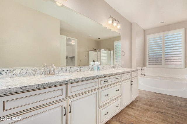 18108 W Cassia Way, Goodyear, AZ 85338 - bathroom featuring a stall shower, double vanity, a garden tub, and wood finished floors