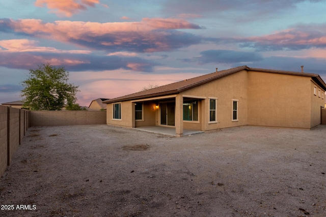 18108 W Cassia Way, Goodyear, AZ 85338 - back of property at dusk with a fenced backyard, a patio area, and stucco siding
