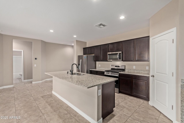 kitchen featuring stainless steel appliances, an island with sink, sink, and dark brown cabinetry