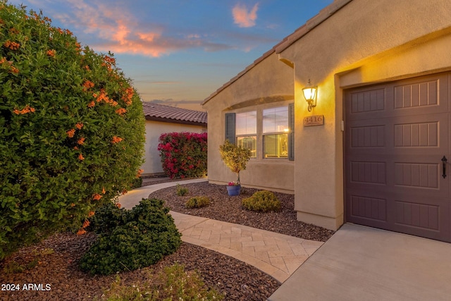 exterior entry at dusk featuring a garage