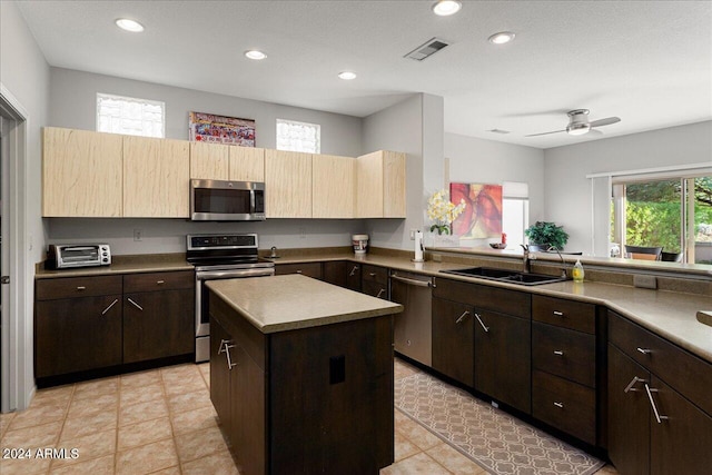 kitchen with ceiling fan, light tile patterned flooring, sink, appliances with stainless steel finishes, and a center island