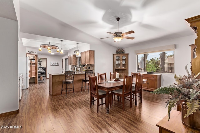 dining area with dark wood-type flooring, ceiling fan, and vaulted ceiling