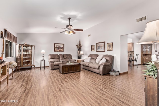 living room featuring vaulted ceiling, ceiling fan, and light hardwood / wood-style flooring