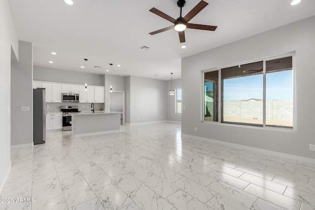 unfurnished living room with ceiling fan with notable chandelier and sink