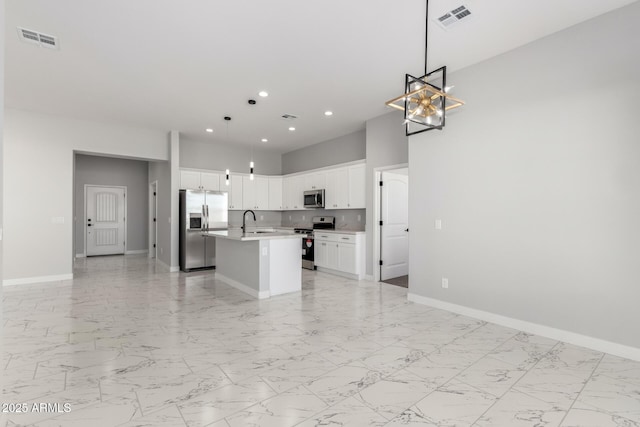 kitchen featuring white cabinets, sink, an island with sink, decorative light fixtures, and stainless steel appliances