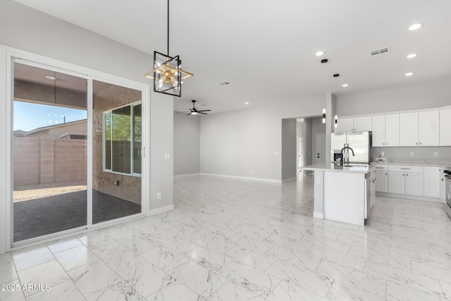 kitchen featuring stainless steel fridge, white cabinetry, ceiling fan, and pendant lighting