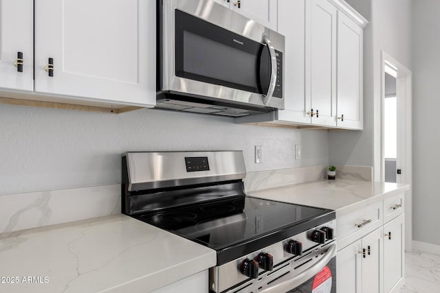 kitchen with light stone counters, white cabinets, and appliances with stainless steel finishes