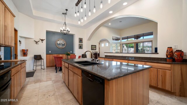 kitchen featuring black appliances, hanging light fixtures, an island with sink, a notable chandelier, and sink