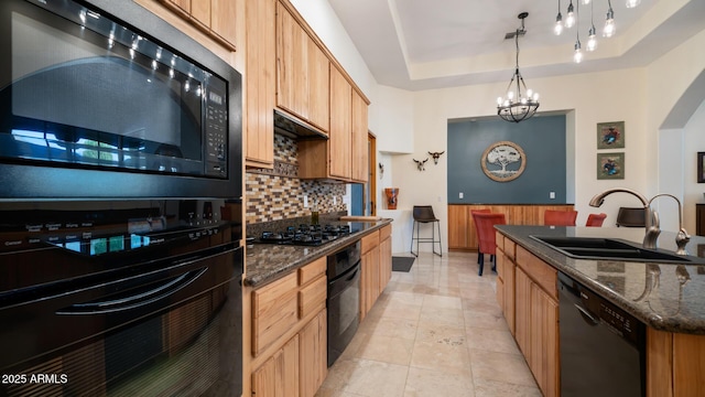 kitchen with pendant lighting, black appliances, an inviting chandelier, a tray ceiling, and sink