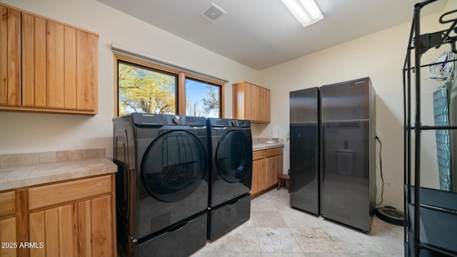 clothes washing area featuring cabinets and washing machine and clothes dryer