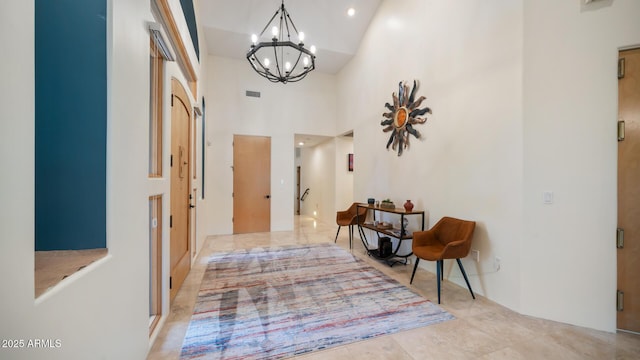 hallway with a towering ceiling and an inviting chandelier