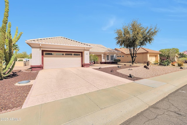 view of front of home with a garage, a tile roof, concrete driveway, and stucco siding